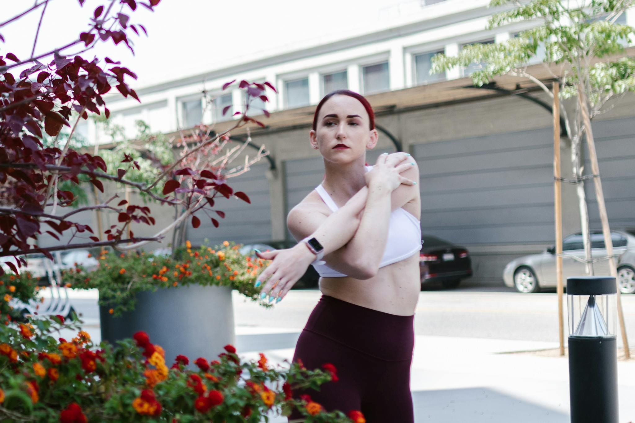 Caucasian woman in activewear stretching outdoors, showcasing fitness in the city.